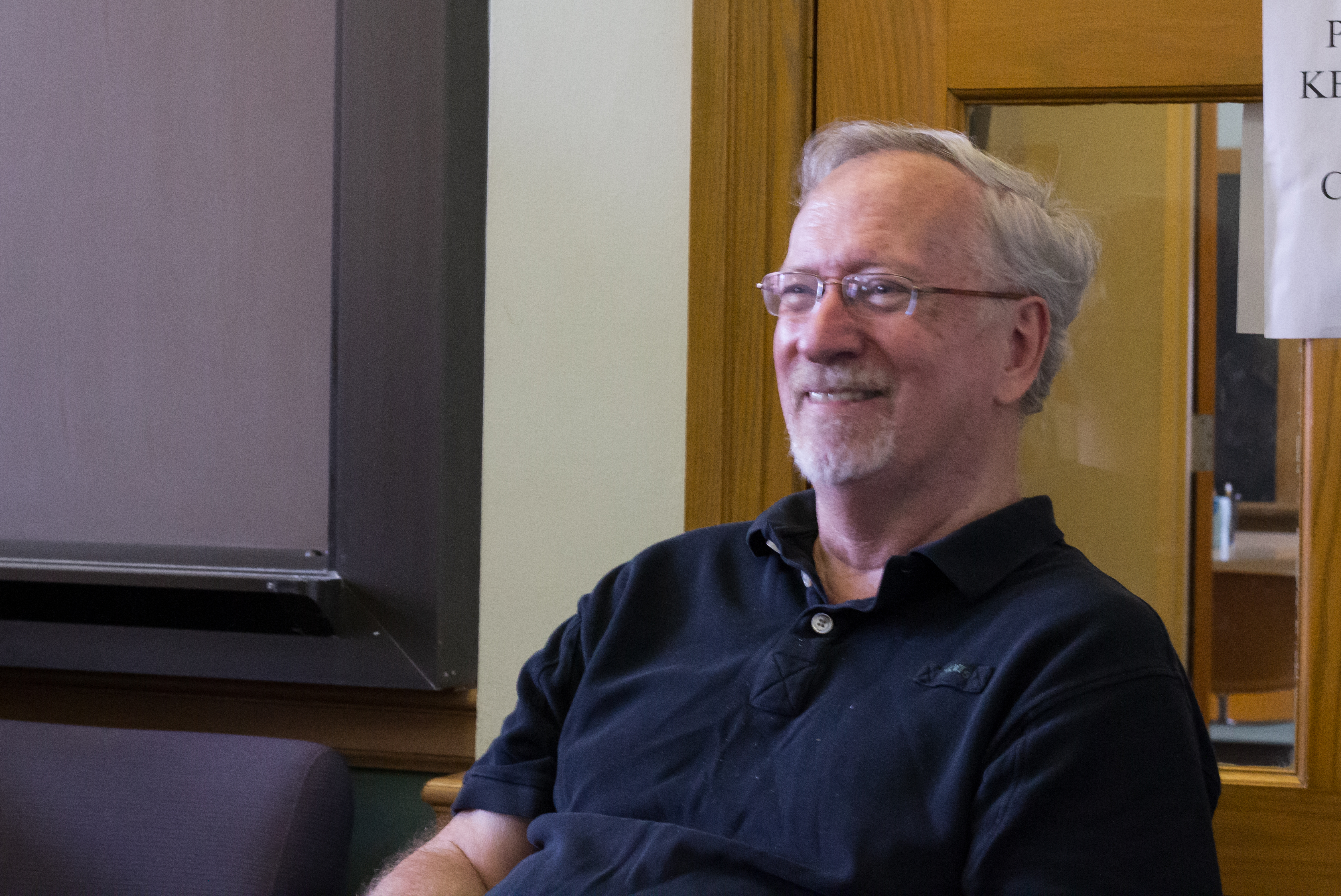 Our director, Ed Lotto, sits in a chair, smiling, during a meeting with the writing tutors.