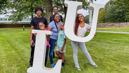Family posing with large LU letters at Orientation Check-in
